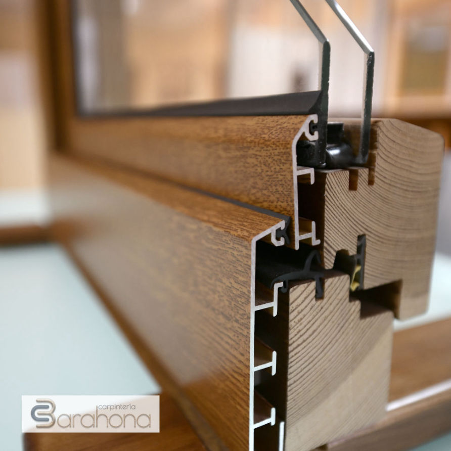 Detalle de sección de ventana mixta con estructura de madera y perfilería interior de aluminio, mostrando el sistema de anclaje y aislamiento. Carpintería Barahona.